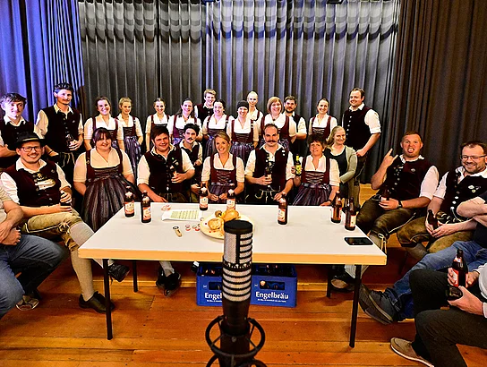Einige Personen sitzen um einen Tisch. Gruppenbild nach den Aufnahmen zum Lied "Fast as a Shark".