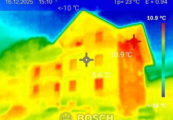 Die Thermografische Aufnahme zeigt eine Hausfassade komplett in gelb-orange. Der Hintergrund ist blau. Das Bild wurde mit einer Wärmebildkamera aufgenommen.