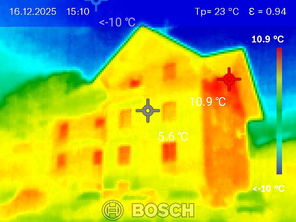 Die Thermografische Aufnahme zeigt eine Hausfassade komplett in gelb-orange. Der Hintergrund ist blau. Das Bild wurde mit einer Wärmebildkamera aufgenommen.
