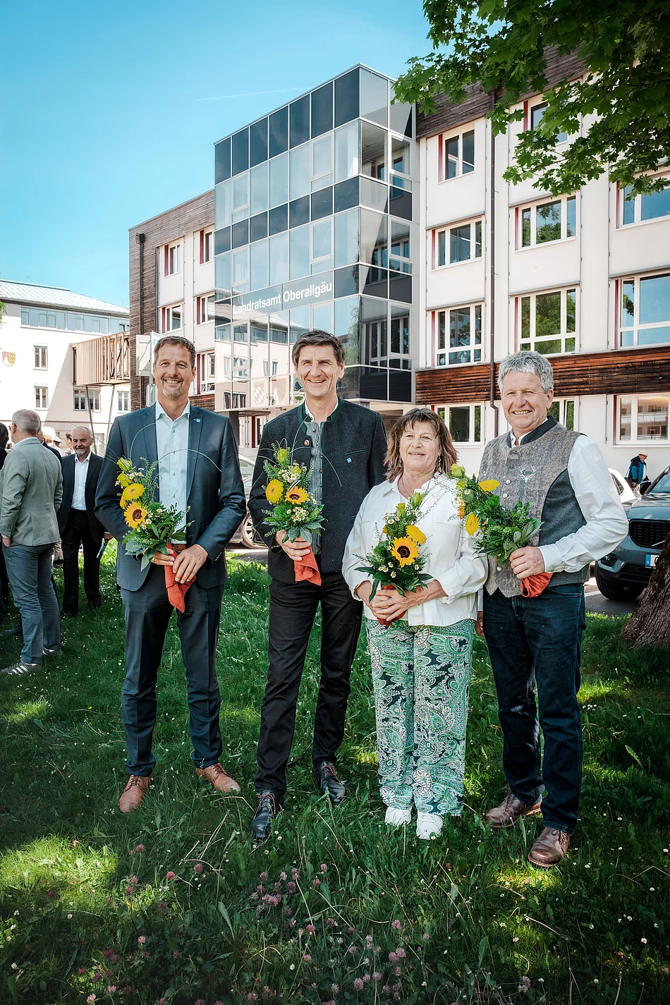 Landrat Christian Wilhelm mit seinen Stellvertretern Landrat Christian Wilhelm mit seinen Stellvertretern Gerhard Frey, Christine Rietzler und Norbert Meggle. Sie stehen vor dem Gebäude des Landratsamtes Oberallgäu und halten jeder einen kleinen Blumenstrauß in den Händen.